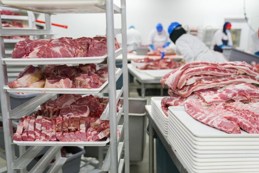 Trabalhadores processam cortes de carne suína em uma unidade industrial de alimentos.